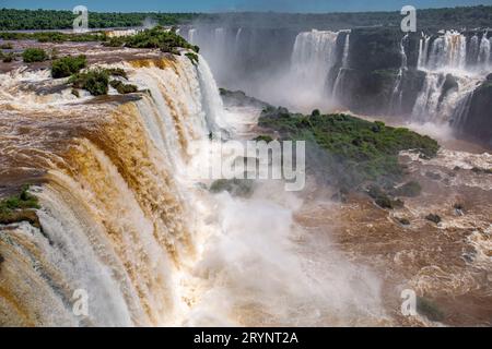 Blick auf die mächtigen Iguazu-Fälle in der Nähe von DevilÂ Hals mit braunem und weißem Wasser in üppiger grüner Vegetation Stockfoto