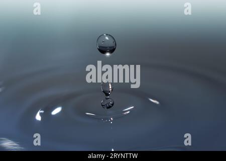 Klare Wassertropfen aus Aqua, die in konzentrischen Kreisen spritzen und erfrischende Reinheit einfangen. Stockfoto