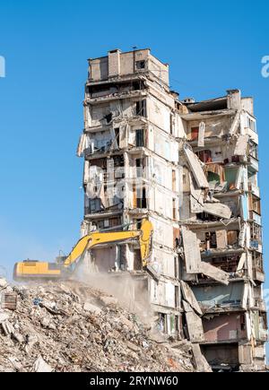 Baumaschinen zerstören Häuser, die während des Krieges in der Ukraine beschädigt wurden Stockfoto