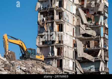 Baumaschinen zerstören Häuser, die während des Krieges in der Ukraine beschädigt wurden Stockfoto