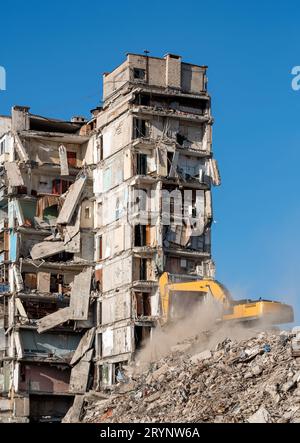 Baumaschinen zerstören Häuser, die während des Krieges in der Ukraine beschädigt wurden Stockfoto