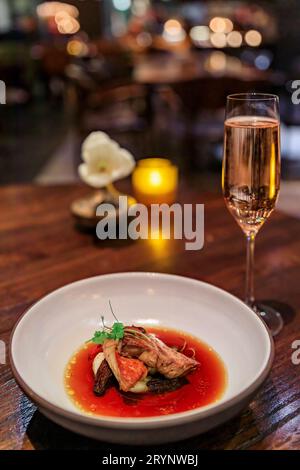 Ein Glas Sekt auf einem Tisch in einem edlen Restaurant mit Kerze und Tulpenblüte in Seattle, Washington, USA Stockfoto