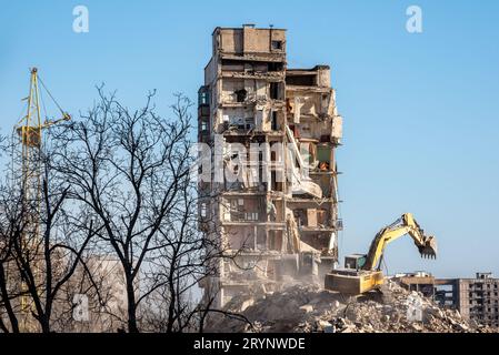 Baumaschinen zerstören Häuser, die während des Krieges in der Ukraine beschädigt wurden Stockfoto