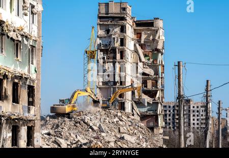 Baumaschinen zerstören Häuser, die während des Krieges in der Ukraine beschädigt wurden Stockfoto