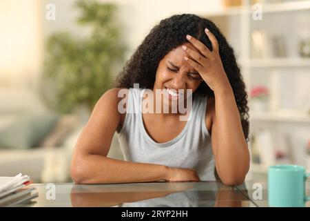 Schwarze Frau, die zu Hause unter Kopfschmerz leidet Stockfoto