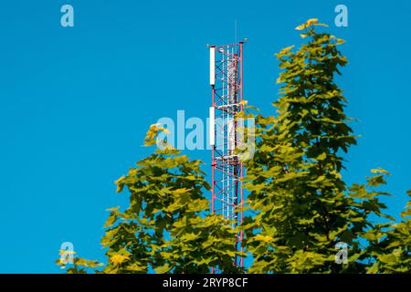 Mast mit Handyantennen gegen klaren blauen Himmel Stockfoto