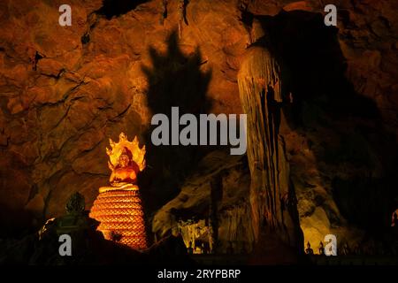 Meditierende Buddha-Statue mit Naga-Schlange (mehrköpfige Königskobra, Mucalinda) und Schatten an der Wand in der Tham Khao Luang Höhle in Phetchaburi, Thailand. Stockfoto