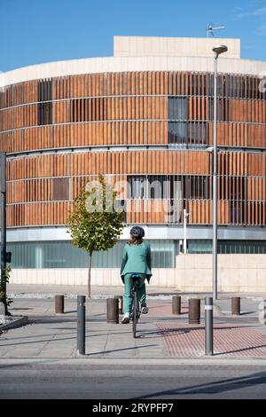 Stilvolle Geschäftsfrau im grünen Anzug, schwarzer Helm, der auf dem Fahrrad auf der Straße fährt Stockfoto