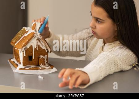 Ein Mädchen spielt mit einem Lebkuchenhaus für traditionelle Weihnachtsdekoration Stockfoto