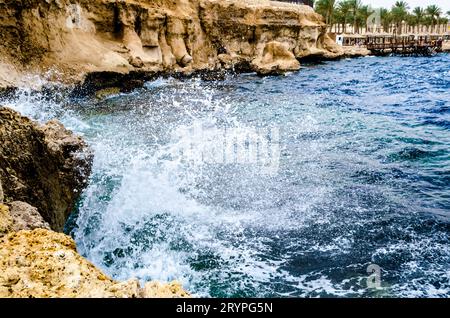 Spritzende Wellen der Brandung, die gegen die Felsen am Strand des roten Meeres krachen Stockfoto