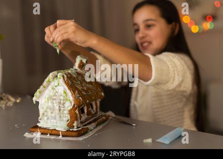 Ein Mädchen spielt mit einem Lebkuchenhaus für traditionelle Weihnachtsdekoration Stockfoto