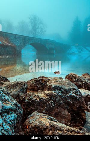 Alte Steinbrücke am Bohinjer See am nebeligen Morgen, ruhige Szene von Sloweniens Reiseziel in der Dämmerung, selektiver Fokus Stockfoto