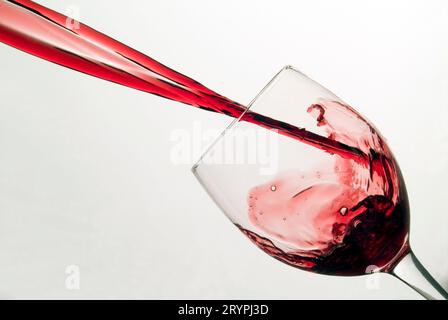 Rotwein spritzt in ein gekipptes Weinglas Stockfoto