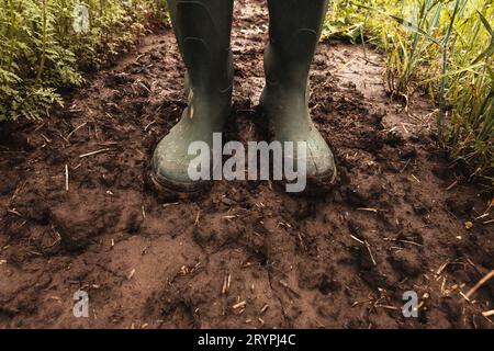 Schmutzige Gummistiefel in matschigem Boden, Bauer steht nach Regen auf dem Feld, selektiver Fokus Stockfoto