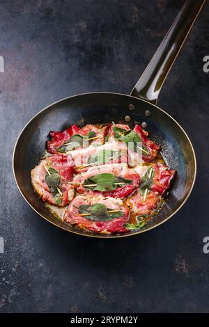 Traditionelles italienisches Schweinefleisch Saltimbocca alla Romana mit Parmaschinken und Salbeiblättern als Nahaufnahme in einer klassischen Pfanne Stockfoto