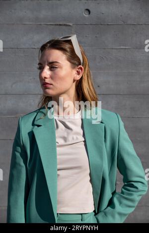 Junge Frau mit Ingwerbehaarung im grünen Anzug und weißer Sonnenbrille auf schwarzem Hintergrund Stockfoto
