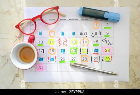 Kalender mit Geschäftsterminen, Stiften, Kaffeetasse und Brille, monatlicher Zeitplan. Geschäftskonzept, die Uhr überholen. Stockfoto