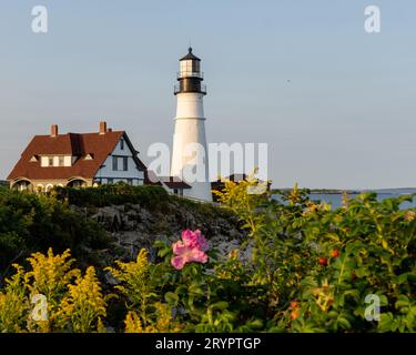 Ein majestätischer weißer Leuchtturm steht hoch auf einer felsigen Klippe und blickt auf eine weite Fläche mit glitzerndem blauem Meer Stockfoto