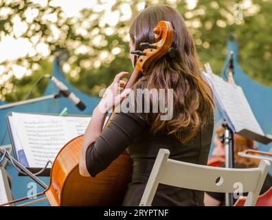 Junge Brünette, die auf der Straße Cello spielt Stockfoto