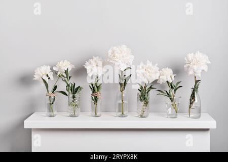 Elegante weiße Pfingstrosen-Blumenarrangements am Kamin. Minimalistische Einrichtung mit Blumenmuster Stockfoto