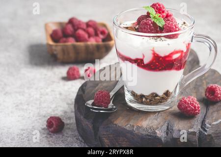 Himbeerschicht Dessert oder Frühstück mit natürlichem Joghurt in einer Glasbecher und Reifen Himbeeren Stockfoto