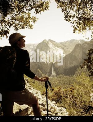 Ein Wanderer blickt von der verlassenen, historischen Old Big Oak Flat Road im Yosemite Valley auf die Bridal Veil Falls. Stockfoto
