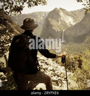 Ein Wanderer blickt von der verlassenen, historischen Old Big Oak Flat Road im Yosemite Valley auf die Bridal Veil Falls. Stockfoto