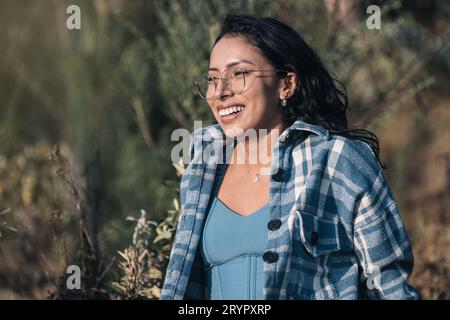 Eine schöne junge Frau mit Brille lächelt beim Sonnenuntergang in der Natur Stockfoto