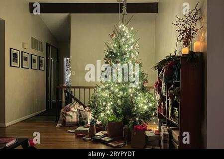Eingewickelte Geschenke unter einem wunderschön beleuchteten weihnachtsbaum. Stockfoto