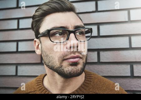 Porträt eines gutaussehenden kaukasischen Mannes mit Brille, der ernsthaft die Stirn runzelt. Emotionales Gesichtskonzept. Stockfoto