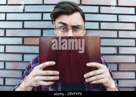 Portrait von lächelnden stattlicher Mann in runde Gläser und Shirt isoliert auf braun Mauer. Stockfoto