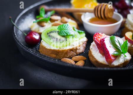 Verschiedene süße Snacks im Sommer. Bruschetta oder Sandwiches mit Früchten Stockfoto