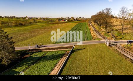 Ein Aerial View eines Amish Horse and Buggy, der an einem sonnigen Herbsttag auf einer Landstraße auf eine Rail Road Crossing fährt Stockfoto