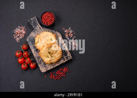 Köstliche frittierte Fischschnitzel oder Fleischbällchen mit Salz, Gewürzen und Kräutern auf dunklem Betonhintergrund Stockfoto