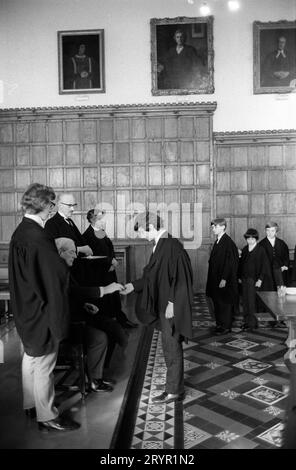 Eton College, Kings Scholars stellen sich zusammen und sammeln ihr jährliches traditionelles 3D-Stück vom College Provost. Diese Tradition, die als Threepenny Day bekannt ist, ist 400 Jahre alt. Die jährliche Verteilung erfolgte nach dem Mittagessen in der College Hall durch den Provost Harold Caccia (Provost 1965–1977) und war auf die siebzig Könige Gelehrten beschränkt. Eton, Windsor, Berkshire, England, 27. Februar 1975. 1970ER JAHRE UK HOMER SYKES Stockfoto