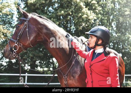 Junge hübsche Jockey Mädchen Pferd für die Fahrt vorbereiten. liebe Pferde Stockfoto