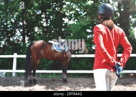 Junge hübsche Jockey Mädchen Vorbereitung Pferd für reiten. Liebe Pferde. Close-up Rückansicht Stockfoto