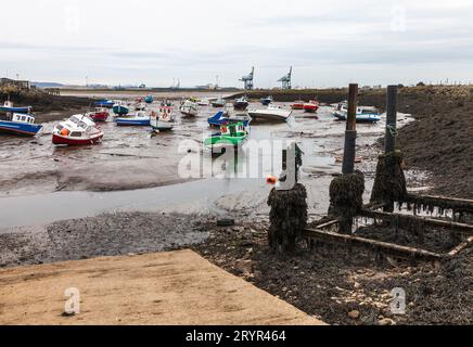 Ein Blick von Paddys Hole, Redcar mit den vertäuten Booten und dem industriellen Hintergrund. Ebbe Stockfoto