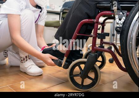 Junge Ärztin unterstützt alte Patientin mit Behinderung, die im Rollstuhl sitzt, weibliche Betreuerin oder Krankenschwester Stockfoto