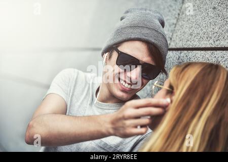 Junge attraktive Paare, die Musik auf denselben Kopfhörern hören, in stilvoller Kleidung vor einem Hintergrund eines Stockfoto