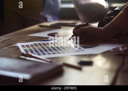 Nahaufnahme von Innenarchitekten arbeiten mit Hausbauplänen auf dem Schreibtisch zusammen, Architekten arbeiten mit Farbpaletten Stockfoto