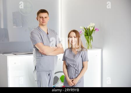Zwei Zahnärzte stehen an der Rezeption in einer wunderschönen Klinik und begrüßen die Patienten. Junges Team von Spezialisten Stockfoto
