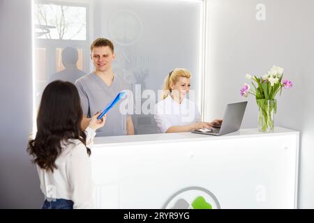 Ein junges hübsches Mädchen kam in die Klinik und sprach mit Ärzten an der Rezeption Stockfoto