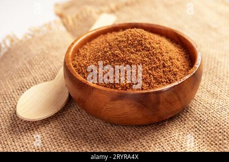 Bio-brauner Kokospalmenzucker in Holzschüssel und Bambuslöffel auf einem Sacktuch Stockfoto