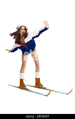 Porträt einer jungen Frau, die Vintage-Tuch, Mantel, Stiefel und Hut trägt, die auf Skiern steht, Skifahren auf Pisten isolierter weißer Studiohintergrund. Stockfoto