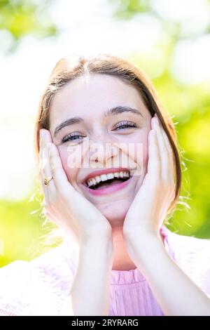 Eine fröhlich lachende junge Frau mit perfekter Haut, natürlichem Make-up und einem schönen Lächeln. Lifestyle-Konzept mit positivem Emotio Stockfoto