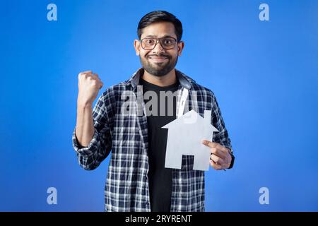 Immobilien, Hypotheken, Versicherungen. Ein fröhlicher Mann, der ein Hausmodell hält. Stockfoto