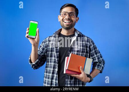 Glücklicher Student, Smartphone, leerer Bildschirm, Handy in der Hand. Indischer Erwachsener zeigt Smartphone mit leerem grünem Bildschirm. Stockfoto