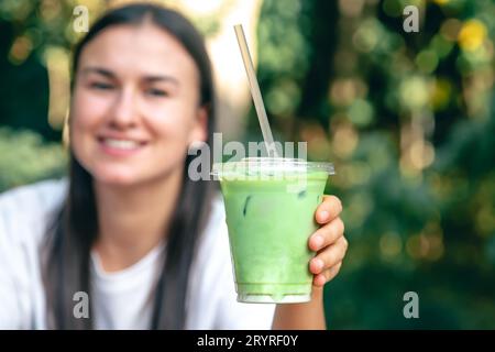 Gefrorener Matcha Latte in einem Plastikbecher in den Händen einer Frau. Stockfoto