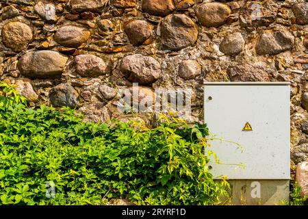 Elektroschaltschrank gegen eine raue Steinwand Stockfoto